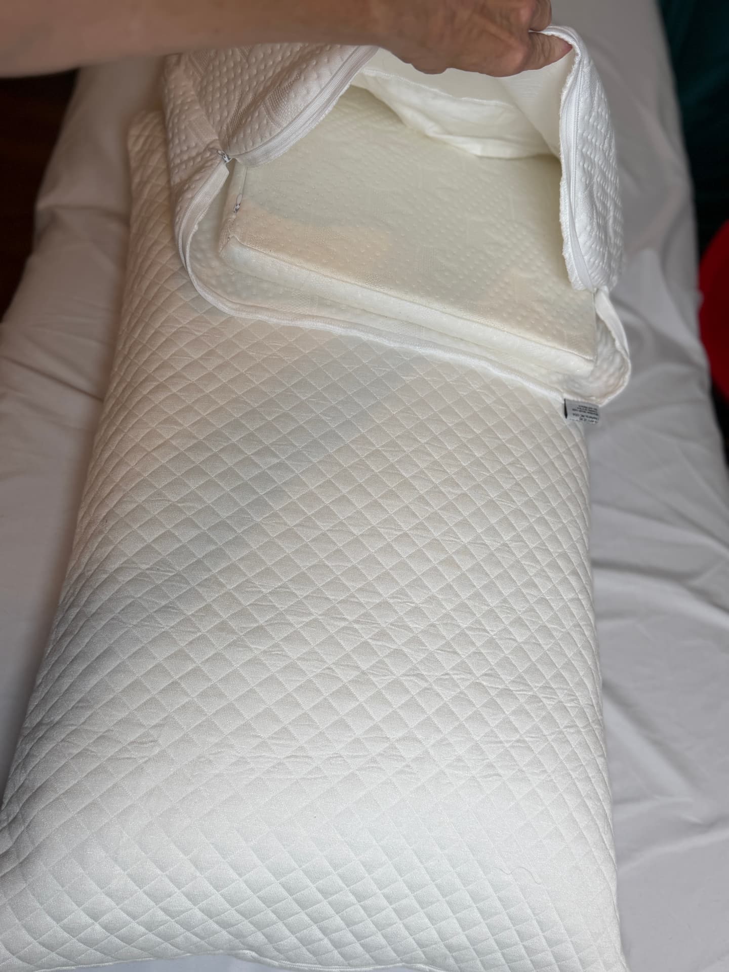 A Crown Lift support core being slid into the zippered pocket pillowcase over an everyday pillow.
