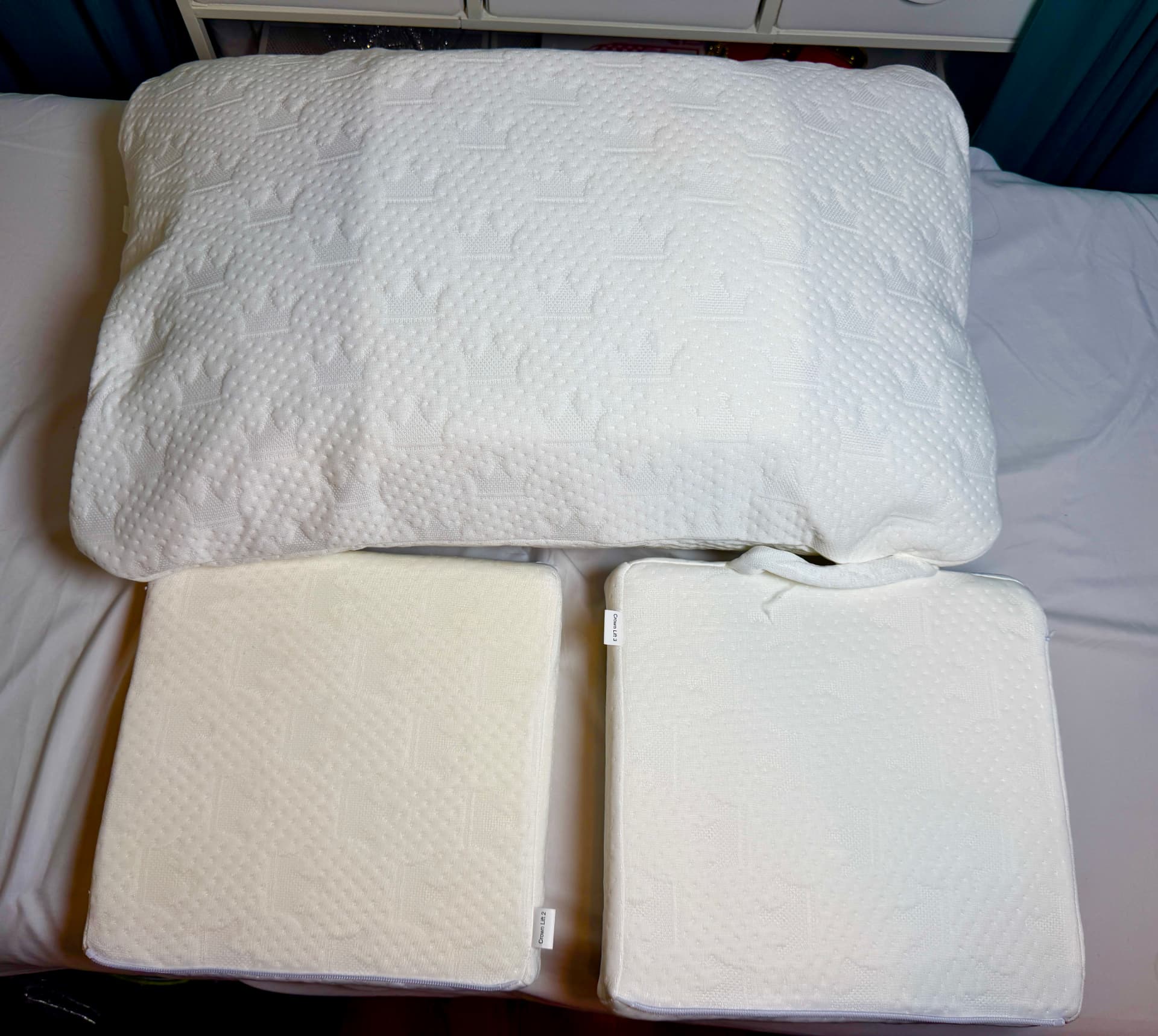 A Crown Lift pocket pillowcase on a bed with two support cores laid out in front of it.